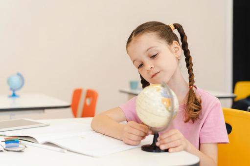 傾げて地球儀を見る女の子 女の子,子ども,人物の写真素材