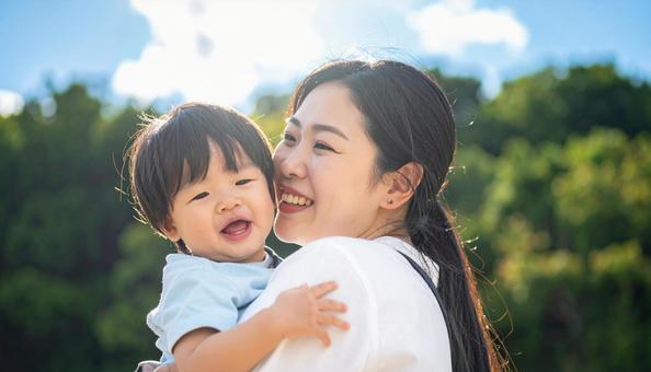 青空の下、子供を抱っこする母親 青空の下、子供を抱っこする母親の写真