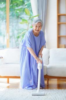 カメラ目線で掃除機を持つ青い服の女性 女性,掃除,掃除機の写真素材