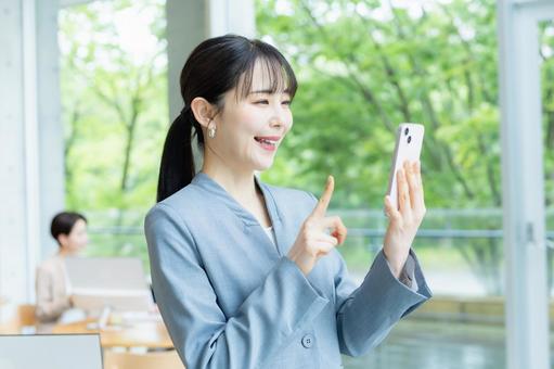 スマホを操作するビジネスウーマン スマホを操作するビジネスウーマン スマホ,笑顔,ビジネスウーマンの写真素材