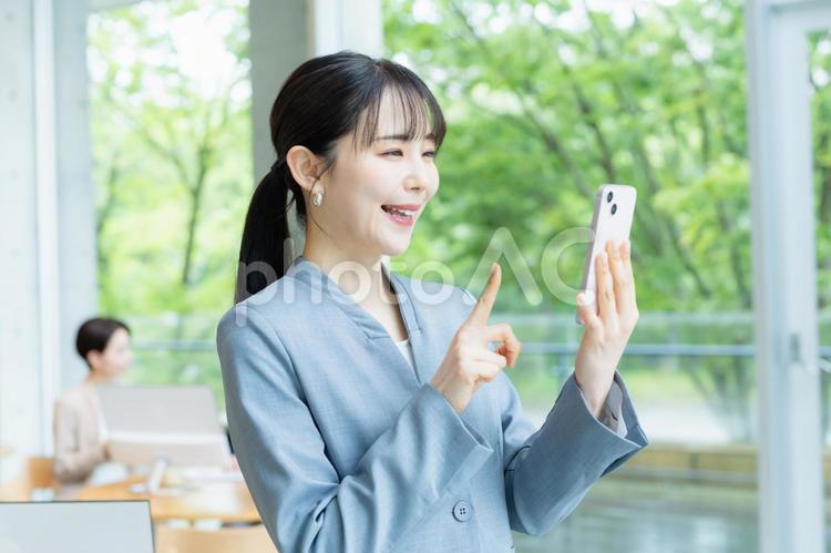 スマホを操作するビジネスウーマン スマホ,笑顔,ビジネスウーマンの写真素材