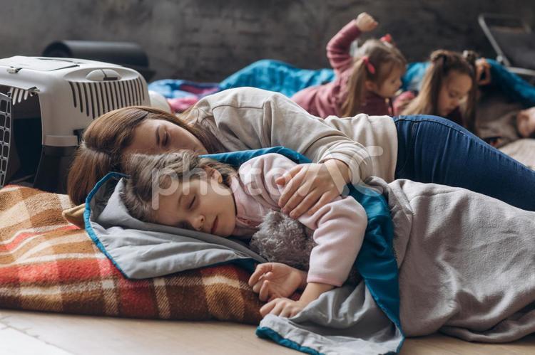 添い寝する女性と女の子と後ろで何かを見ている女の子 女性,女の子,人物の写真素材