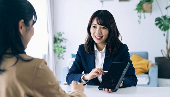 タブレットを使って説明する女性営業マンの写真