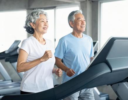 ランニングマシンで走る仲良しシニア夫婦 ランニングマシンで走る仲良しシニア夫婦の写真