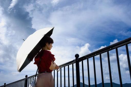 <素材>夏の海沿いの防波堤を散策する女性 <素材>夏の海沿いの防波堤を散策する女性の写真