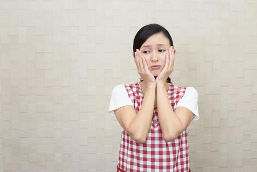 困惑するエプロン姿の女性 困惑するエプロン姿の女性の写真
