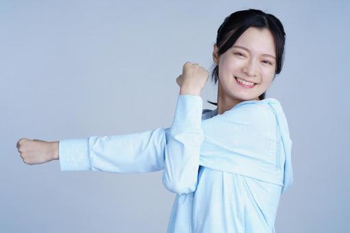 水色の服の女性が笑顔で腕を伸ばす 女性,腕を伸ばす,ストレッチの写真素材