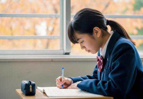 秋の教室で勉強に集中する女子学生の写真