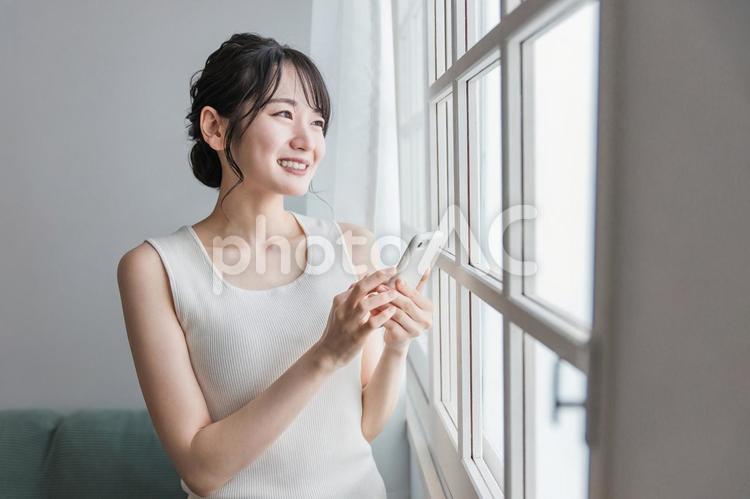 家でスマホを使うアジア人女性（SNS) スマホ,スマートフォン,snsの写真素材