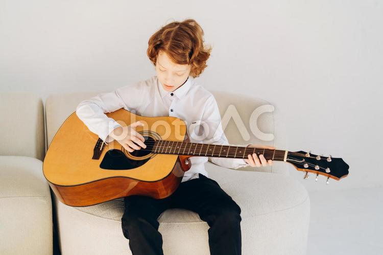 ソファーに座ってギターを練習する男の子 男の子,人物,練習の写真素材