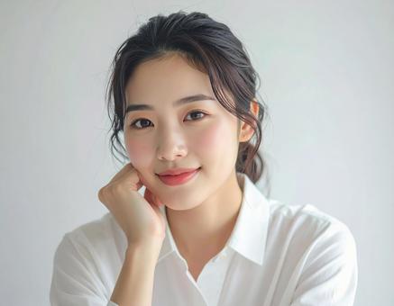 笑顔で頬杖をつく若い女性 笑顔で頬杖をつく若い女性の写真