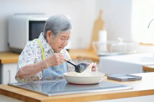 フライパンで料理中のおばあちゃん 女性,料理,フライパンの写真素材