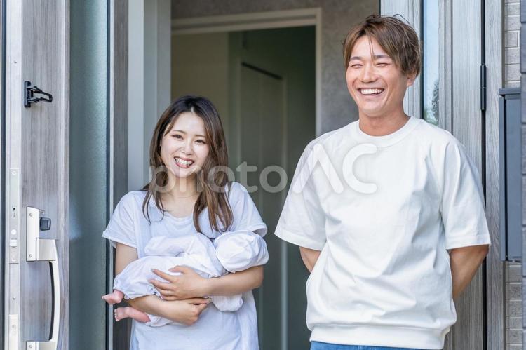玄関で出迎える赤ちゃんを抱っこする夫婦 家,夫婦,玄関の写真素材