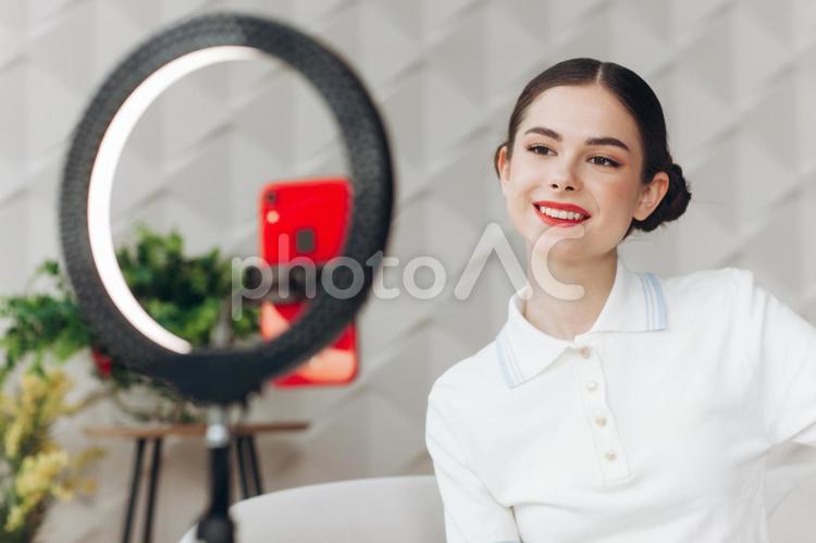 笑顔で配信する女性と観葉植物 女性,ポロシャツ,赤の写真素材