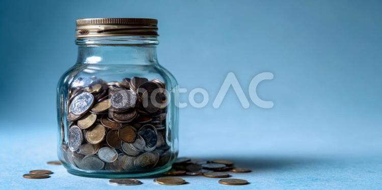 青い背景に輝く、コインが詰まった貯金瓶 貯金箱,コイン,硬貨の写真素材