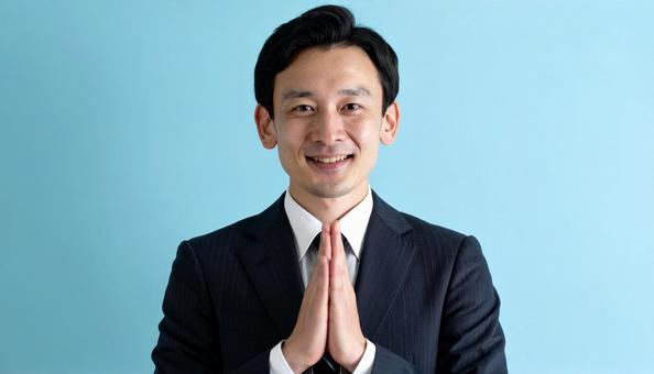 両手をあわせてお願いしているビジネスマン 両手をあわせてお願いしているビジネスマンの写真