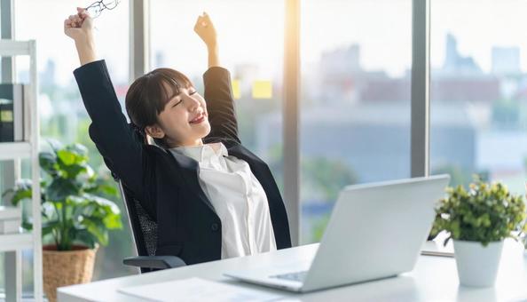 仕事が終わり達成感で背伸びをする社員 仕事が終わり達成感で背伸びをする社員の写真