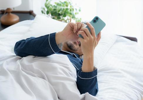 寝室でスマホを見るミドルの男性 寝室でスマホを見るミドルの男性 男性,スマホ,ミドルの写真素材