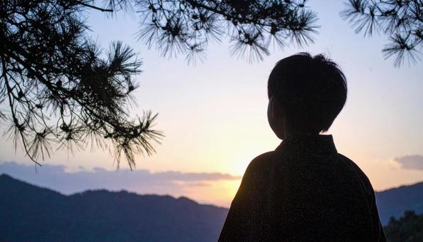 夕焼けの空を見つめる日本人の少年 夕焼けの空を見つめる日本人の少年の写真