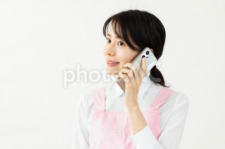 電話をするエプロン姿のアジア人女性02 保育士,女性,エプロンの写真素材