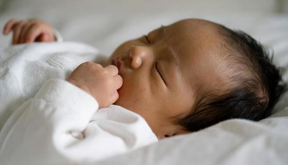 寝ながら指しゃぶりをする子供の横顔 寝ながら指しゃぶりをする子供の横顔の写真