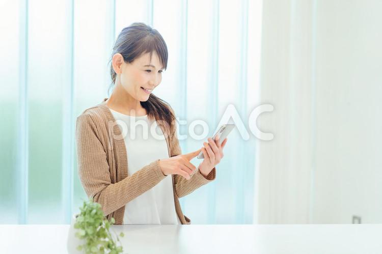 スマホを使う中高年の女性（アプリ・動画・笑顔） 主婦,スマートフォン,アプリの写真素材