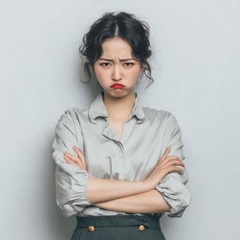 不満そうな表情で腕組みをする日本人 不満そうな表情で腕組みをする日本人の写真