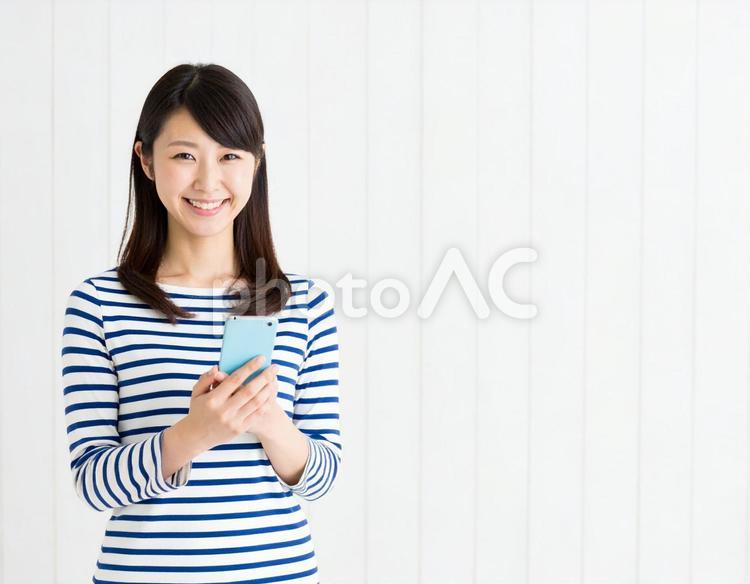 室内でスマートフォンを持つ笑顔の女性 女性,笑顔,人物の写真素材