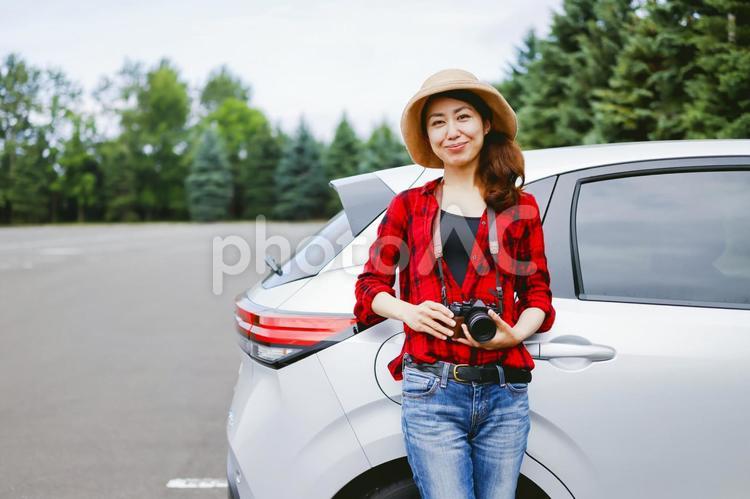 車とカメラを持つ女性 カメラ,一眼レフ,ドライブの写真素材