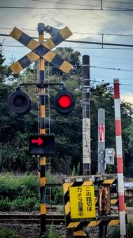 夕暮れの空に光る赤信号の踏切 夕暮れの空に光る赤信号の踏切 踏切,鉄道,線路の写真素材