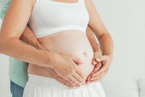 妊婦のお腹を触る夫婦の手元 妊婦のお腹を触る夫婦の手元の写真