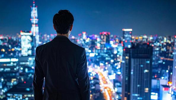 都市の夜景を背景に佇むビジネスマン 都市の夜景を背景に佇むビジネスマンの写真