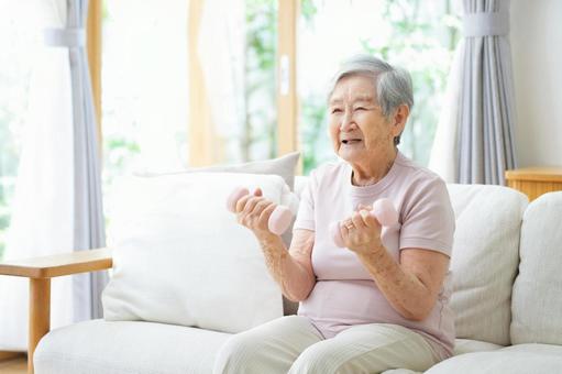 両手にダンベルを持ち筋トレ中の女性の写真