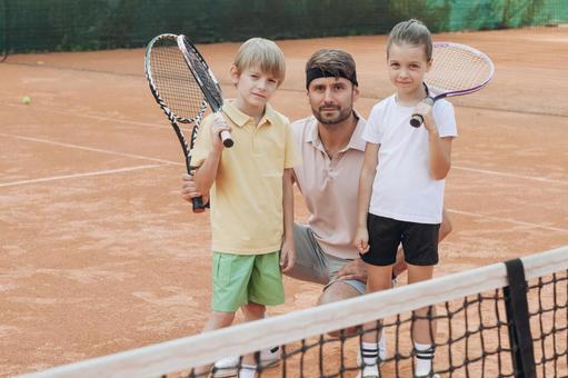 ネット越しに笑顔のコーチと子供の写真