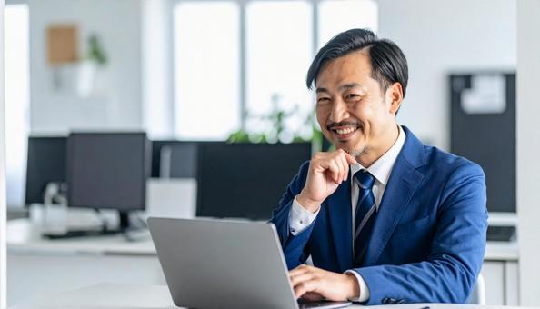 パソコンの前で閃く笑顔の男性社員の写真