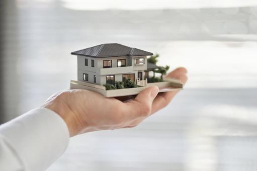 Hands of an Asian man holding an architectural model of a single house, building model, house, detached house, JPG