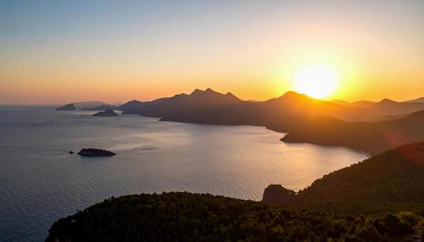 海の向こうの山に沈む夕日の絶景 海の向こうの山に沈む夕日の絶景の写真