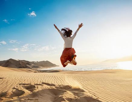 砂漠でジャンプする女性の写真