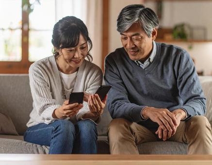リビングでスマホを見るシニア夫婦 リビングでスマホを見るシニア夫婦の写真