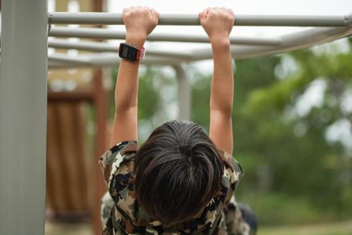 <素材>秋の公園で雲梯にぶら下がる男の子 <素材>秋の公園で雲梯にぶら下がる男の子の写真