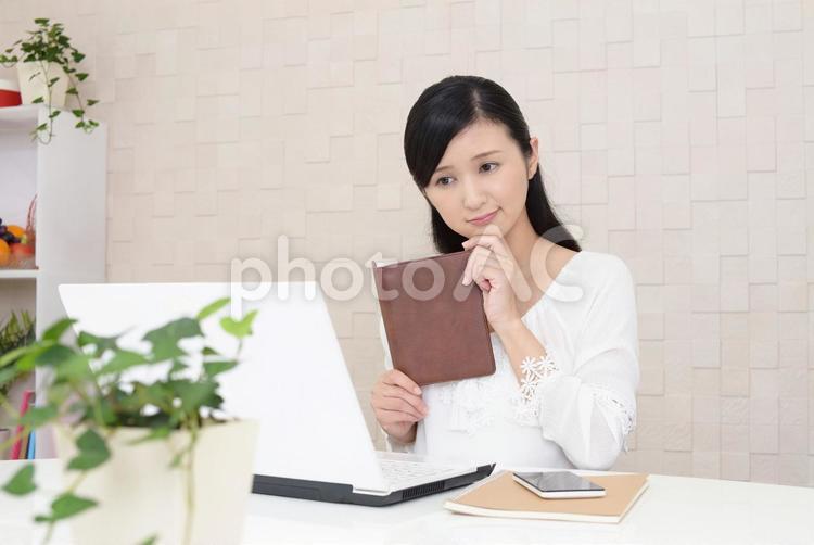 不安そうな表情の女性 女性,女,ノートパソコンの写真素材