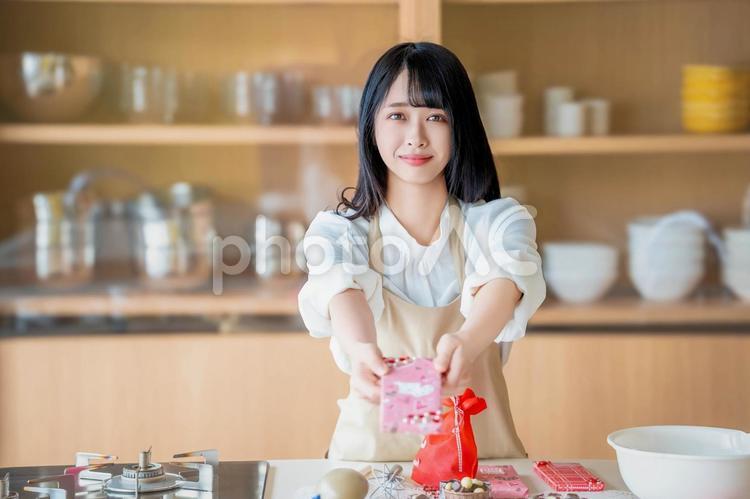 義理チョコを渡すエプロン姿の女性 バレンタイン,チョコ,手作りチョコの写真素材