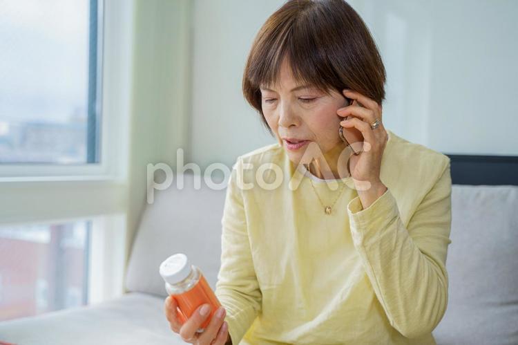 スマホで薬の飲み方を聞くシニア女性 女性,日本人,薬の写真素材
