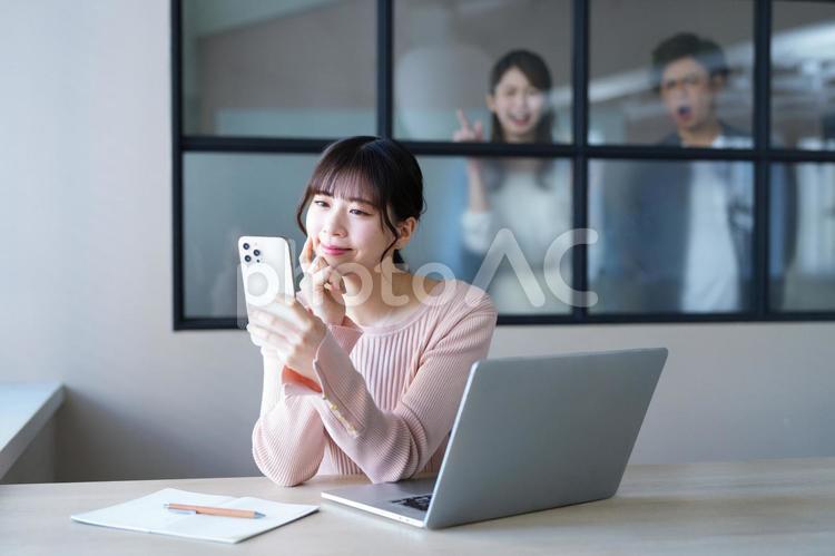 仕事中にスマホを見る女性を見つけた男女 女性,スマートフォン,持つの写真素材