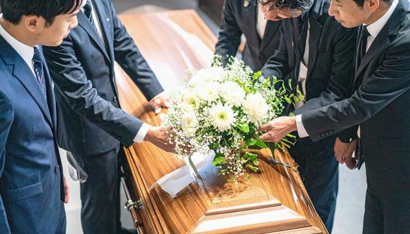 葬式でお棺に白い花束を入れる人の手もと 葬式でお棺に白い花束を入れる人の手もとの写真