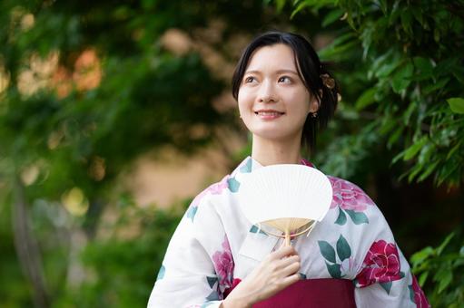 浴衣姿の女性が両手で団扇を持つ 女性,浴衣,団扇の写真素材