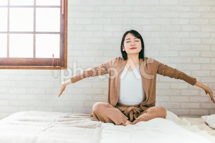 ベッドルームにいる女性（起床・深呼吸） ベッド,起床,起きるの写真素材