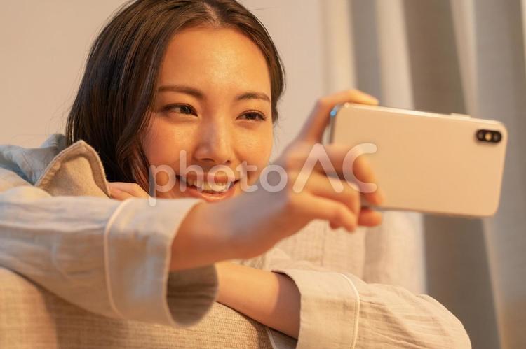 寝室で携帯を見る女性 女性,若い,夜の写真素材