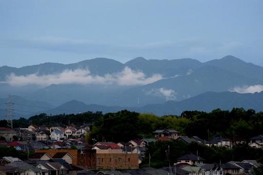 住宅地の向こうの雲がかかる山並み 住宅地の向こうの雲がかかる山並みの写真