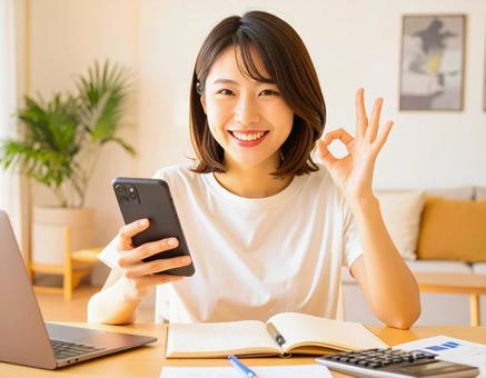 家計がうまくいきスマホ片手に微笑む女性 家計がうまくいきスマホ片手に微笑む女性の写真